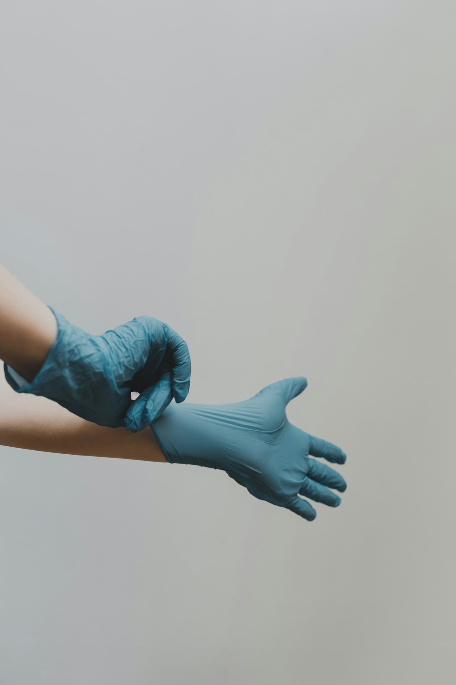 Hände ziehen blaue Schutzhandschuhe an – Vorbereitung auf den Reinigungseinsatz